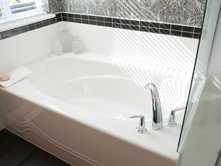 Corner, deep circular bathtub with corner faucet and small black tiles