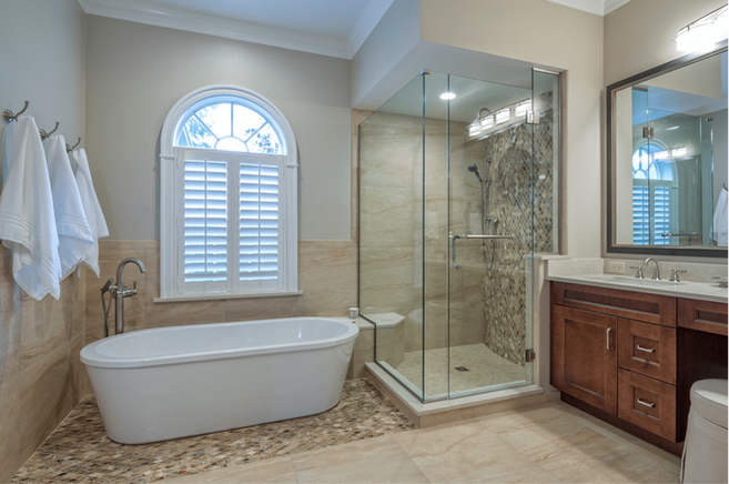 Whole remodeled bathroom with standalone tub, glass-walled shower, and wooden-style vanity